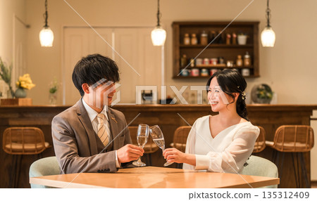 一對穿著得體的情侶在餐廳或酒吧一邊喝香檳一邊交談。 135312409