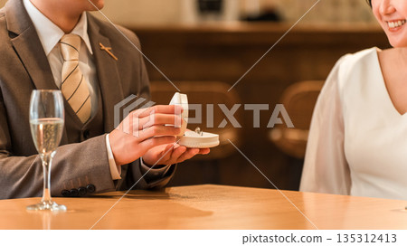 一名男子在餐廳向女子求婚,女子收到一枚戒指。 一名男子在餐廳向女子求婚,女子收到一枚戒指。 135312413