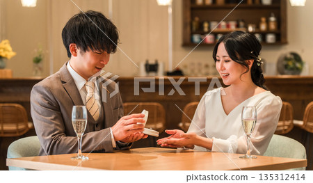 一名男子在餐廳向女子求婚,女子收到一枚戒指。 一名男子在餐廳向女子求婚,女子收到一枚戒指。 135312414