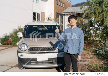 微笑的男子雙手交叉抱在胸前，站在他的車前。 135312452