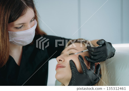 an aesthetic professional performing an injection procedure. Beauty treatment an aesthetic professional performing an injection procedure. Beauty treatment 135312461