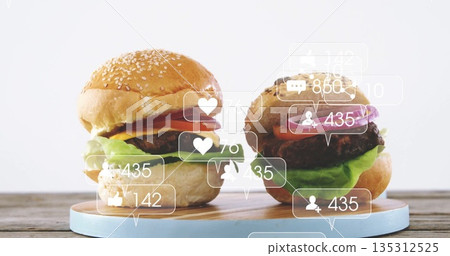 Stacking beef burgers layering lettuce tomato cheese onion on wood board, with social media icons 135312525