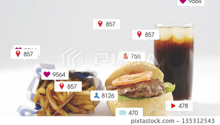 Displaying cheeseburger with lettuce and tomato by fries and cola on table, with notification icons Displaying cheeseburger with lettuce and tomato by fries and cola on table, with notification icons 135312543