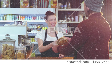 Barista wearing black apron handing loaf of bread at coffee shop counter, with espresso and cookies Barista wearing black apron handing loaf of bread at coffee shop counter, with espresso and cookies 135312562