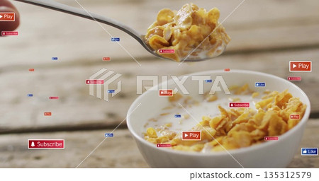 Lifting spoonful of cornflakes from milk bowl on tabletop, subscribe like play icons, copy space 135312579