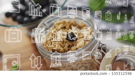 Glass jar topped by dark berry sitting on wooden table in kitchen, with grapes, digital icons 135312596