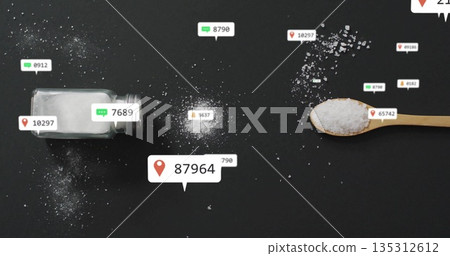 Spilling glass salt shaker and wooden spoon sprinkling crystals on matte table with data icons 135312612