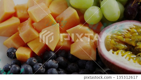 Displaying fruit on kitchen counter, featuring papaya cubes, passionfruit, blueberries and grapes 135312617