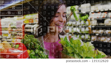 Shopper wearing pink top holding bag of greens in produce aisle, with headphones, currency overlay Shopper wearing pink top holding bag of greens in produce aisle, with headphones, currency overlay 135312620