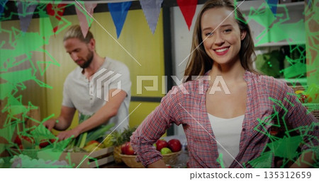 Smiling woman wearing pink shirt standing at market counter, with man chopping produce, copy space 135312659