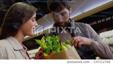 Inspecting couple holding brown paper bag in supermarket aisle, with leafy greens and bananas Inspecting couple holding brown paper bag in supermarket aisle, with leafy greens and bananas 135312708