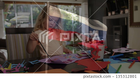 Painting preschool girl using brush on paper at dining table, with palette and markers Painting preschool girl using brush on paper at dining table, with palette and markers 135312801