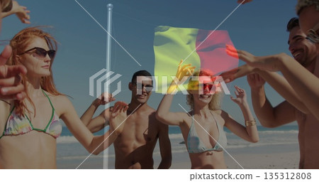 Dancing friends in swimwear raising hands around flagpole on beach, with waving tricolor flag 135312808