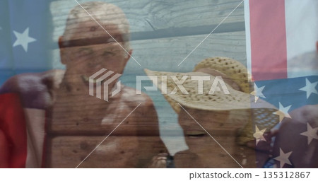 Smiling group of seniors in swimwear posing at beach shoreline, with straw sun hat, US flag Smiling group of seniors in swimwear posing at beach shoreline, with straw sun hat, US flag 135312867