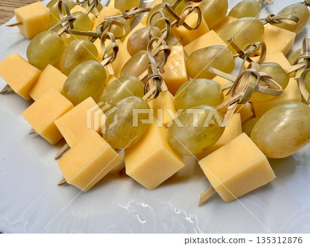 New Year's snack skewers hard cheese with grapes on the festive table New Year's snack skewers hard cheese with grapes on the festive table 135312876
