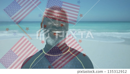 Smiling mature man in wetsuit standing on beach, with semi-transparent US flags and star overlays Smiling mature man in wetsuit standing on beach, with semi-transparent US flags and star overlays 135312912