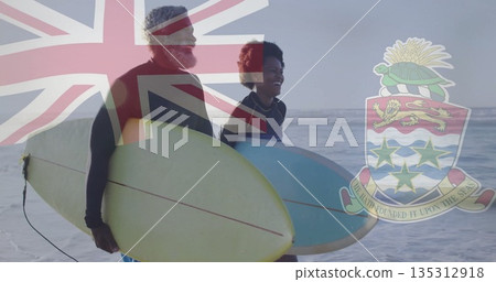 Walking couple wearing wetsuits into Cayman Islands shore, holding yellow and light blue surfboards Walking couple wearing wetsuits into Cayman Islands shore, holding yellow and light blue surfboards 135312918