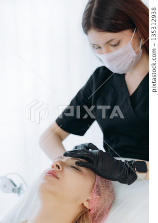 professional cosmetic doctol preparing to make a rejuvenation injection into woman frown line 135312938