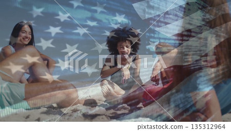 Smiling friends sitting on sandy beach, with sunglasses beach towel straw hat American flag overlay Smiling friends sitting on sandy beach, with sunglasses beach towel straw hat American flag overlay 135312964