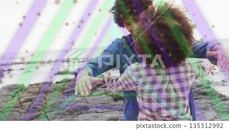 Embracing couple wearing denim and plaid hugging on rocky shore, with ocean waves and light overlay Embracing couple wearing denim and plaid hugging on rocky shore, with ocean waves and light overlay 135312992