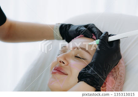 aesthetician marking a client face with a medical-grade marker before anti-aging injections aesthetician marking a client face with a medical-grade marker before anti-aging injections 135313015
