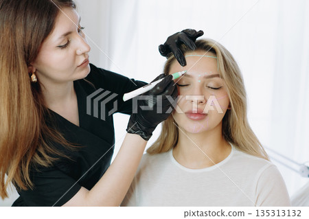 aesthetician marking a client face with a medical-grade marker before anti-aging injections aesthetician marking a client face with a medical-grade marker before anti-aging injections 135313132