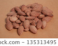 Almonds rest on a simple piece of paper, highlighting their natural texture in a clean minimal scene. 135313495