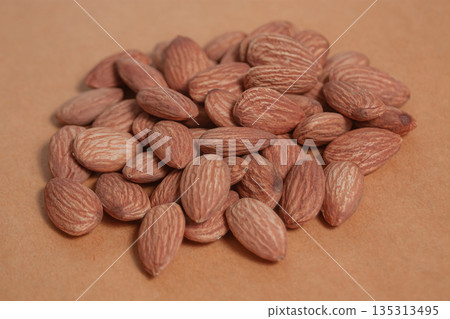 Almonds rest on a simple piece of paper, highlighting their natural texture in a clean minimal scene. 135313495