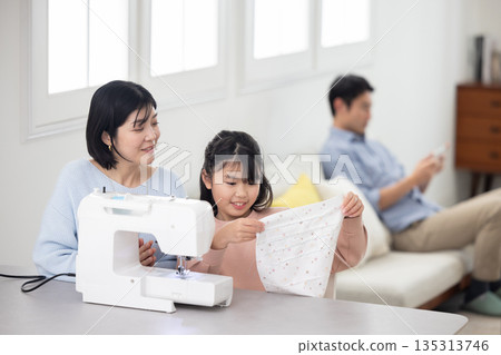 一個小學生女孩和她媽媽一起縫紉 135313746