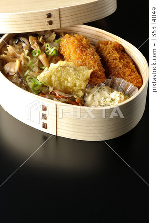 Mushroom rice and fried oyster bento photographed against a black background Mushroom rice and fried oyster bento photographed against a black background 135314049