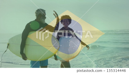 Walking couple in wetsuits exchanging greeting along sandy beach shoreline, with white surfboards Walking couple in wetsuits exchanging greeting along sandy beach shoreline, with white surfboards 135314446