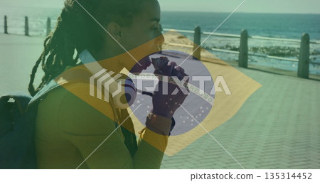 Eating snack, woman in yellow top standing on seaside walkway, with headphones, copy space Eating snack, woman in yellow top standing on seaside walkway, with headphones, copy space 135314452