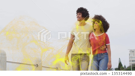Strolling couple linking arms by concrete waterfront railing, swirling yellow particles, copy space 135314490
