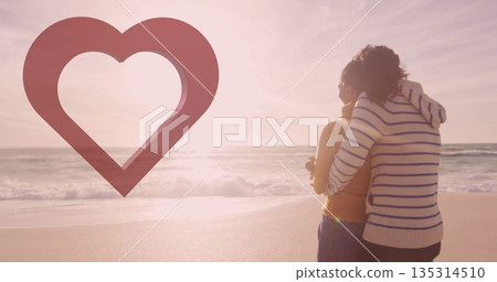 Embracing couple wearing sweater and orange tank on beach, with waves, heart graphic, copy space Embracing couple wearing sweater and orange tank on beach, with waves, heart graphic, copy space 135314510