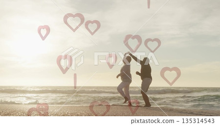 Dancing older couple twirling along beach shore at sunset, with heart-shaped overlays, copy space Dancing older couple twirling along beach shore at sunset, with heart-shaped overlays, copy space 135314543