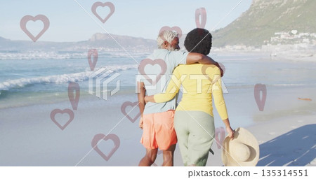 Walking Black couple arm in arm along sandy beach shore, with wide-brimmed straw hat Walking Black couple arm in arm along sandy beach shore, with wide-brimmed straw hat 135314551