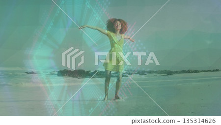 Spinning barefoot woman wearing yellow wrap dress over wet sand at beach with rocky breakwater Spinning barefoot woman wearing yellow wrap dress over wet sand at beach with rocky breakwater 135314626