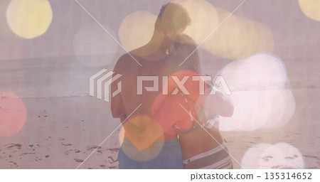 Embracing couple wearing swim trunks, bikini on sandy shore at sunset, holding red inflatable ring Embracing couple wearing swim trunks, bikini on sandy shore at sunset, holding red inflatable ring 135314652