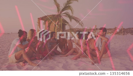 Group of eight friends clinking bottles and glasses on beach at sunset, with lit palm hut Group of eight friends clinking bottles and glasses on beach at sunset, with lit palm hut 135314656
