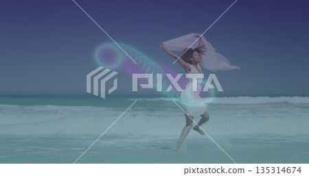 Dancing woman wearing white dress splashing at sunny beach surf, with chiffon scarf and neon spiral Dancing woman wearing white dress splashing at sunny beach surf, with chiffon scarf and neon spiral 135314674