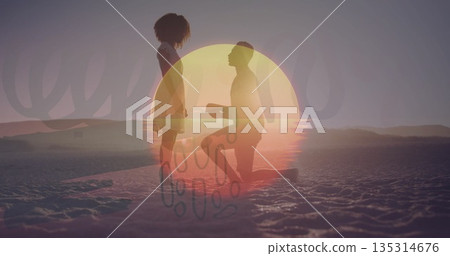 Kneeling man holding ring box for standing woman on salt flat at sunset, with sun overlay Kneeling man holding ring box for standing woman on salt flat at sunset, with sun overlay 135314676