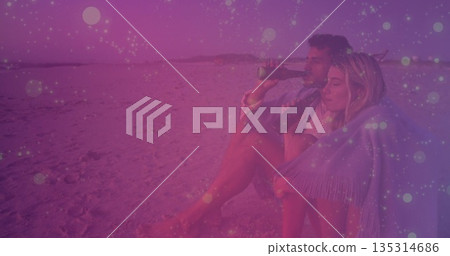 Sitting couple sipping drinks on sandy beach, with fringed shawl and dark bottles, copy space 135314686