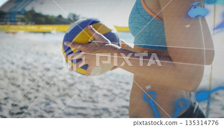 Athlete gripping volleyball at waist in sports bra and shorts on beach court showing volleyball net Athlete gripping volleyball at waist in sports bra and shorts on beach court showing volleyball net 135314776
