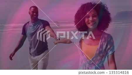 Walking couple holding hands along wet sand by ocean, wearing henley shirt and floral beach dress Walking couple holding hands along wet sand by ocean, wearing henley shirt and floral beach dress 135314816