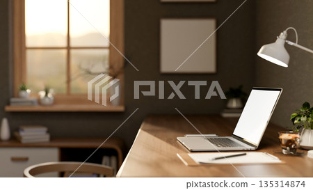 Blank screen laptop with clipboard and coffee cup under lamp on wooden table in a cosy living room. Blank screen laptop with clipboard and coffee cup under lamp on wooden table in a cosy living room. 135314874
