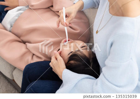 An elementary school girl having her teeth brushed by her mother An elementary school girl having her teeth brushed by her mother 135315039