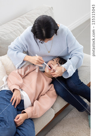 一位小學生正被她的母親刷牙。 一位小學生正被她的母親刷牙。 135315043