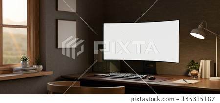 White curved screen computer with stationary and lamp on wooden table in dim living room or office. White curved screen computer with stationary and lamp on wooden table in dim living room or office. 135315187