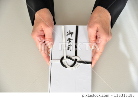 Image of handing over a condolence envelope 135315193