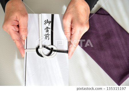 Image of handing over a condolence envelope 135315197